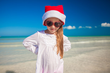 Wall Mural - Little girl in red hat santa claus and sunglasses on the exotic