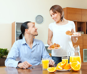 Wall Mural - Smiling woman serves breakfast her  husband