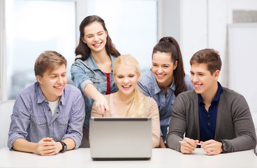 Wall Mural - smiling students looking at laptop at school