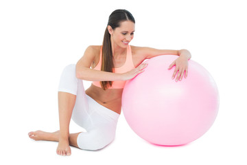 Full length of a fit woman sitting with fitness ball