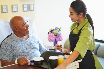 Senior Male Patient Being Served Meal In Hospital Bed