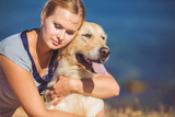 Fototapeta Zwierzęta - Beautiful woman with her dog playing on the sea shore. Outdoor p