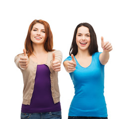 Wall Mural - two smiling girls showing thumbs up