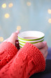 © Africa Studio - Hands holding mug of hot drink, close-up, on bright background