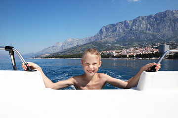 happy girl bathes in sea near boat