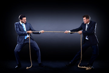 Two business men pulling rope in a competition