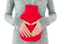 Mid Section Of A Woman Holding Red Hot Water Bag On Abdomen