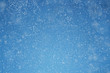 Falling snow over blue background with copy space