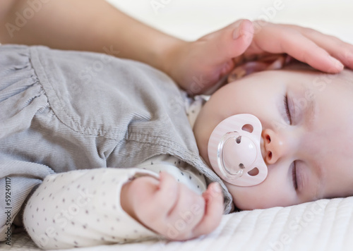 Fotografía Hand of mother caressing her baby girl sleeping