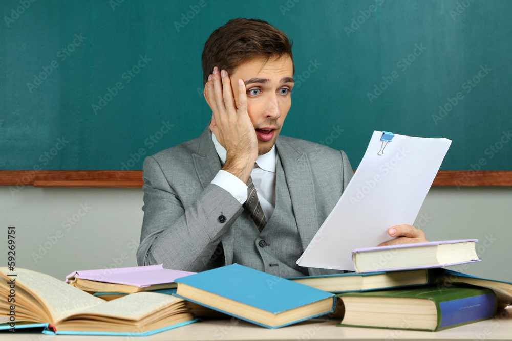 Young teacher sitting in school classroom