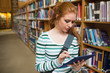 © WavebreakMediaMicro - Focused student using tablet standing in library