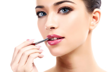 beautiful young woman applying lips makeup with cosmetic brush