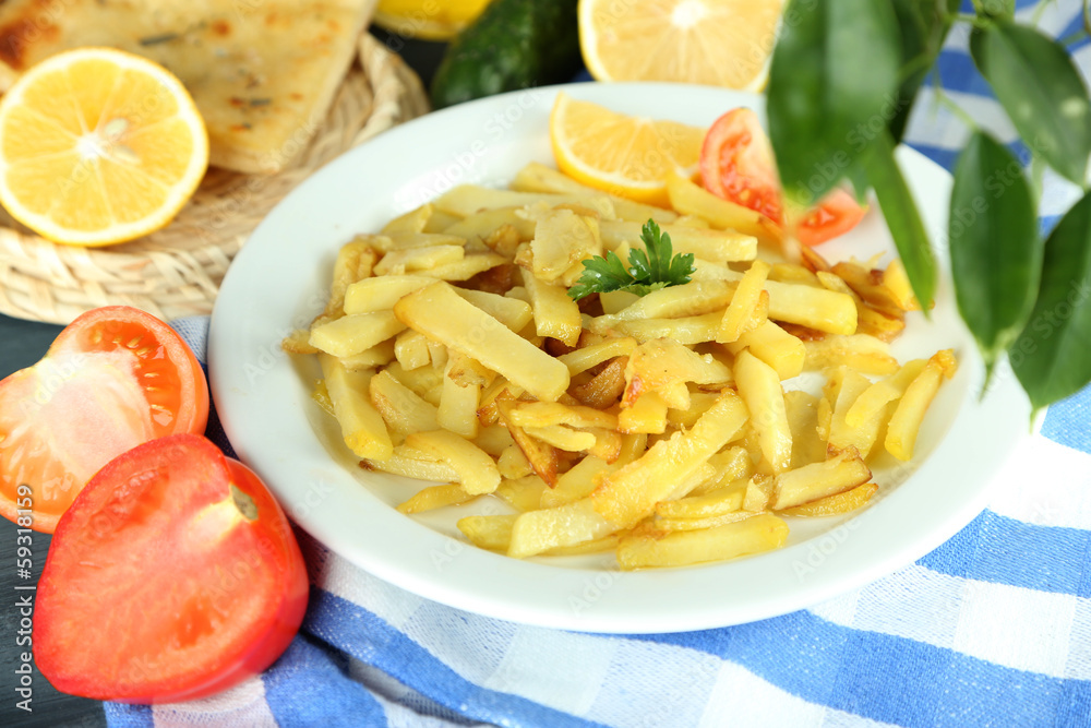 Ruddy fried potatoes on plate on tablecloth close-up