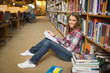 Smiling student reading book on library floor