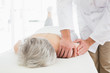 © lightwavemedia - Physiotherapist massaging a senior woman's shoulder