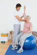 © lightwavemedia - Senior woman on yoga ball with a physical therapist