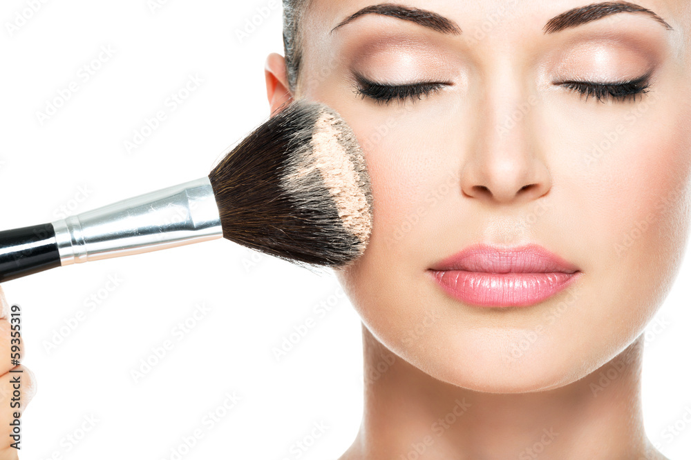 woman  applying dry cosmetic tonal foundation  on the face - obrazy, fototapety, plakaty 