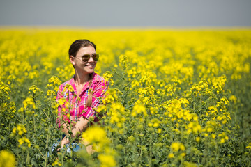 Wall Mural - Young beautiful woman in flowering field in summer. Outdoors