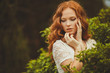 © GTeam - Portrait of young beautiful redhair woman standing in green park