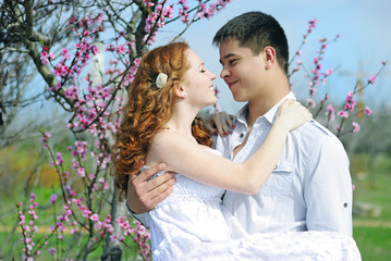 Fototapete - beautiful young couple in love among the flowering trees