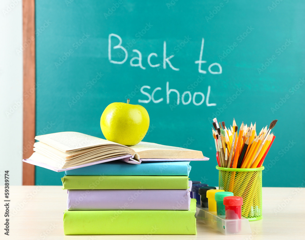 School supplies on table on blackboard background