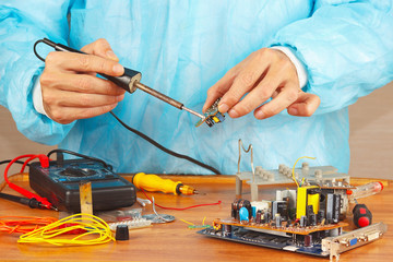 Serviceman solder electronic components of device in workshop