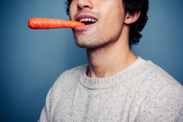 Wall Mural - Young man eating a carrot