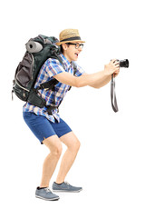 Canvas Print - Male tourist with backpack taking a picture with his camera