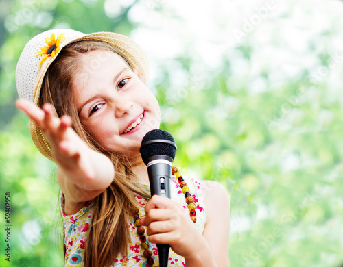 Plakat ładna mała dziewczynka z mikrofonem w dłoniach - na zewnątrz