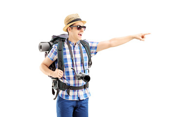 Canvas Print - Smiling male tourist with backpack pointing with his finger