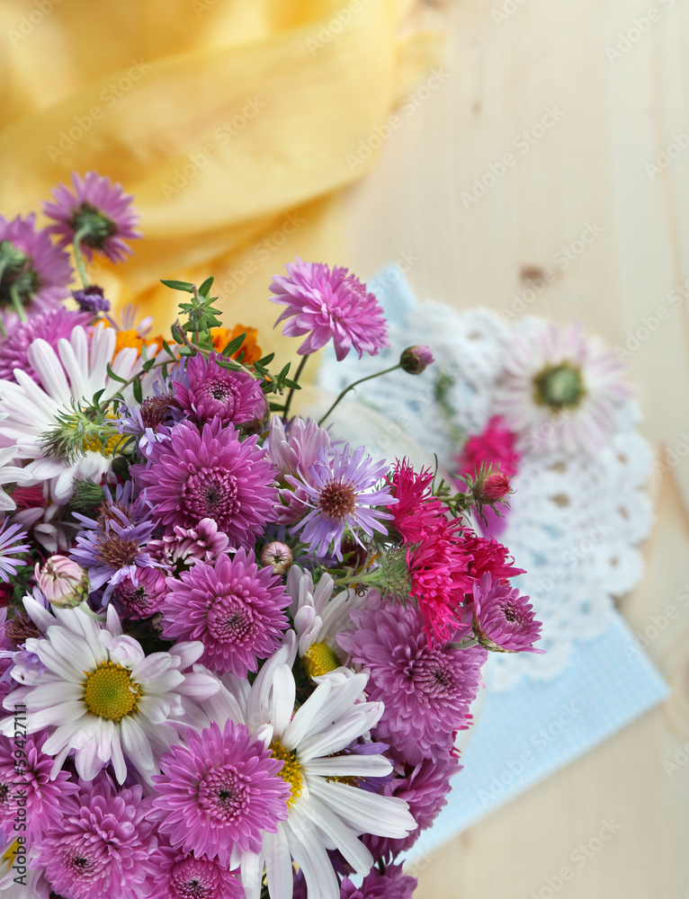 Wildflowers near yellow fabric on wooden background
