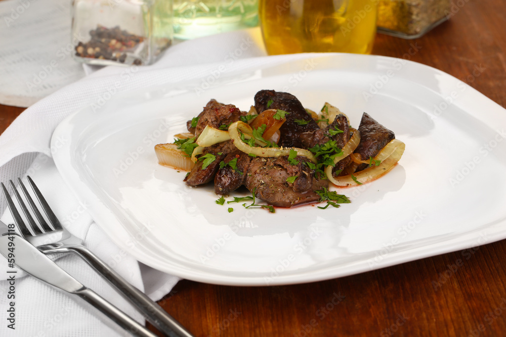 Fried chicken livers on plate on wooden table close-up