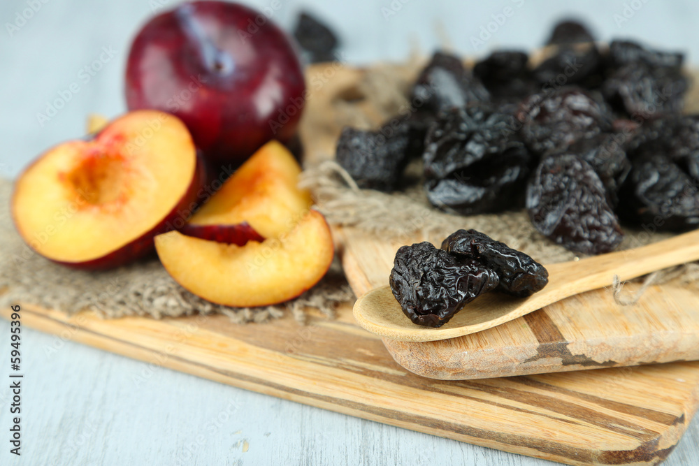 Fresh and dried plums  on napkin, on wooden background