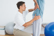 © lightwavemedia - Therapist massaging mans lower back at hospital gym