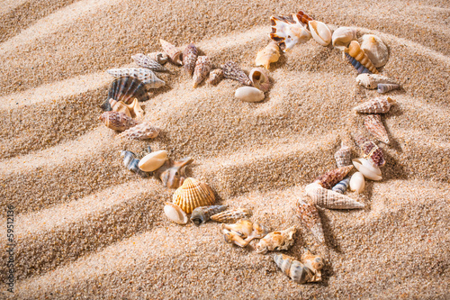 Fototeppich - small seashells in the shape of a heart on a sandy beach (von Alexander Raths)