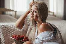 Young Woman Laying On Bed With Strawberry