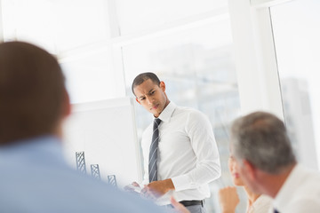 Serious businessman presenting bar chart to co workers