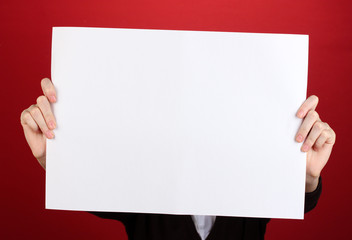 Woman holding blank sign in front her face, on color background