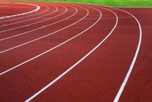 White Lines On Red Running Track With Green Grass.