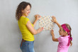 © Pavel Losevsky - Mother and daughter try on finishing tile on the wall