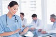 © WavebreakmediaMicro - Surgeon using digital tablet with group around table in hospital