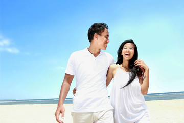 Beach couple in white dress having fun laughing together