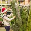 © travnikovstudio - Young man buying green Christmas tree in the market