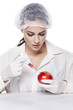 Beautiful chemist woman injected some liquid in red apple