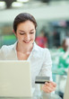 © shefkate - Happy woman sitting on the desk and shopping online