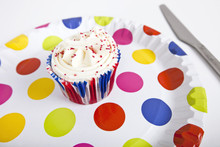 Cupcake In Multicolored Plate With Polka Dots Against White Background