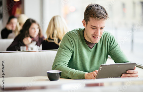 Fotografia Young man / student using tablet computer in cafe