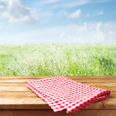 Wall Mural - Wooden table with tablecloth over meadow