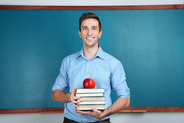 Wall Mural - Young teacher near chalkboard in school classroom