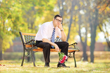 Sad Guy Holding A Bouquet Of Flowers On A Bench In A Park